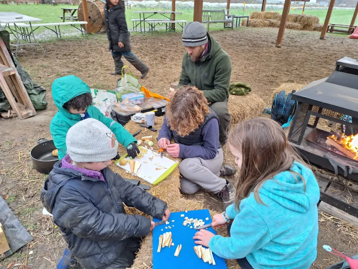 A group gathered around a fire pit with kit bags, preparing for a fire-lighting session